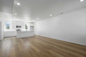 Unfurnished living room featuring sink and light hardwood / wood-style floors