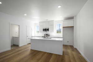 Kitchen featuring a center island with sink, white cabinetry, light wood-type flooring, appliances with stainless steel finishes, and sink