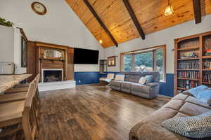 Living room with beam ceiling, a brick fireplace, dark hardwood / wood-style flooring, high vaulted ceiling, and wooden ceiling