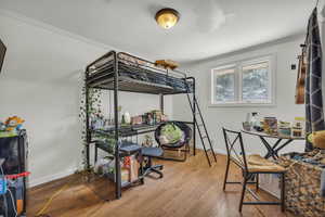 Bedroom featuring hardwood / wood-style flooring and crown molding