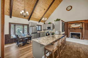 Kitchen featuring decorative light fixtures, hardwood / wood-style flooring, gray cabinets, high vaulted ceiling, and appliances with stainless steel finishes