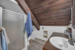 Bathroom with vaulted ceiling, toilet, tile flooring, wood ceiling, and baseboard heating