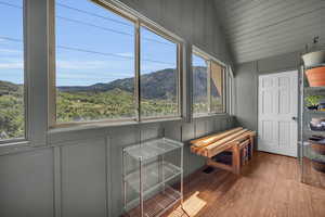 Unfurnished sunroom featuring a mountain view, a healthy amount of sunlight, and lofted ceiling