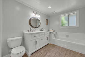 Bathroom featuring hardwood / wood-style flooring, toilet, a bathtub, and crown molding