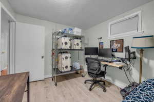 Home office featuring light hardwood / wood-style flooring and a textured ceiling