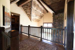 Corridor with wooden ceiling, vaulted ceiling with beams, and wood-type flooring