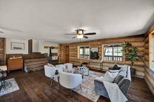 Living room with ceiling fan, log walls, and real hardwood flooring