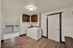 Laundry room with LVP floors, a textured ceiling, cabinets, and washer and clothes dryer