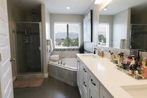 Bathroom featuring a healthy amount of sunlight, separate shower and tub, and double sink vanity