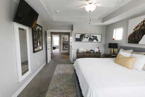 Carpeted bedroom with ceiling fan and a tray ceiling