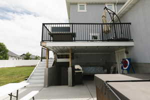 Rear view of property with a patio area, a hot tub, a balcony, and a lawn