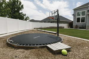 View of basketball court with a lawn and a trampoline