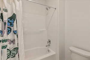 Bathroom with shower / bath combo with shower curtain and toilet