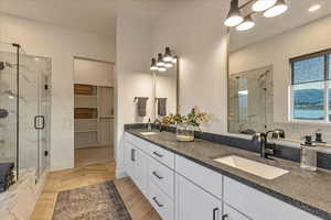 Bathroom featuring a shower with door and double sink vanity