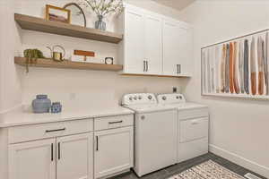 Washroom with separate washer and dryer, dark tile flooring, electric dryer hookup, and cabinets