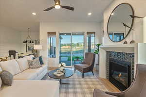 Living room with ceiling fan, a tile fireplace, and light hardwood / wood-style flooring