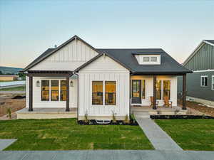 Modern farmhouse style home featuring a porch and a lawn