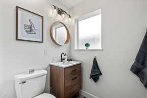 Medium brown vanity, mirror, toilet, shower/bath, and slate grey tiled flooring.