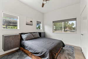 Bedroom featuring built in black/grey end tables, closet, ceiling fan and medium taupe wood type flooring