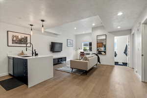 Medium wood type flooring throughout kitchen, living room and office area.