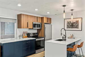 Medium brown and black cabinetry, quartz countertop, built in microwave, and stainless steel finish appliances