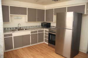 Kitchen featuring stainless steel appliances, gray cabinetry, sink, and light hardwood / wood-style flooring