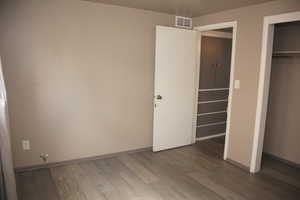 Unfurnished bedroom with a closet and hardwood / wood-style flooring