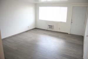 Unfurnished room featuring hardwood / wood-style flooring and an AC wall unit