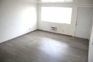 Spare room with a wealth of natural light, a wall mounted air conditioner, and hardwood / wood-style floors