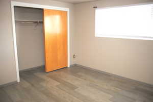 Unfurnished bedroom with a closet and hardwood / wood-style flooring