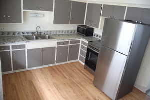 Kitchen with stainless steel appliances, light wood-type flooring, and sink