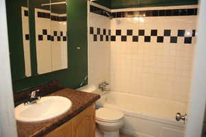 Full bathroom featuring vanity, toilet, and tiled shower / bath combo