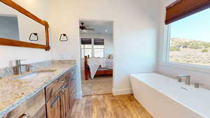 Bathroom featuring a bathtub, ceiling fan, vanity with extensive cabinet space, and wood-type flooring