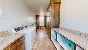 Laundry room featuring separate washer and dryer, hookup for a washing machine, light hardwood / wood-style floors, and cabinets