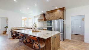 Kitchen with a center island, light hardwood / wood-style floors, stainless steel appliances, premium range hood, and tasteful backsplash