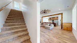 Staircase featuring ceiling fan and light hardwood / wood-style floors