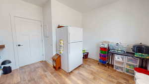 Kitchen with light hardwood / wood-style floors and white fridge