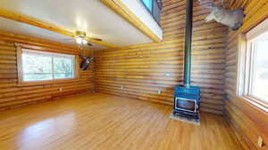 Unfurnished living room with log walls, hardwood / wood-style flooring, and a wood stove