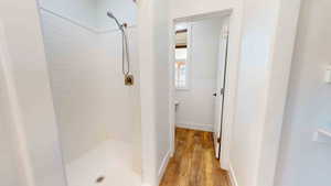 Bathroom featuring a tile shower and wood-type flooring