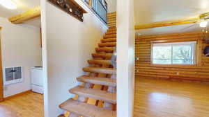 Stairway featuring log walls, ceiling fan, and light wood-type flooring