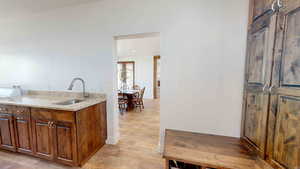 Kitchen with sink, light wood-type flooring, and light stone countertops