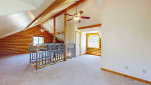 Bonus room featuring carpet flooring, rustic walls, ceiling fan, and lofted ceiling with beams