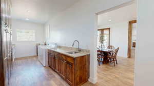 Kitchen with light hardwood / wood-style floors, sink, independent washer and dryer, and light stone counters