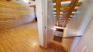 Stairs with ceiling fan, log walls, and light hardwood / wood-style flooring