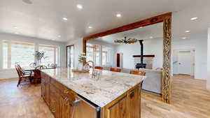 Kitchen with a kitchen island with sink, light wood-type flooring, a wood stove, sink, and a wealth of natural light