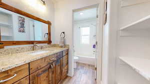 Full bathroom with wood-type flooring, vanity, toilet, and washtub / shower combination