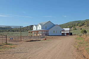 View of front of property featuring a mountain view, covered porch, and a rural view