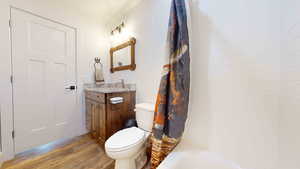 Full bathroom with wood-type flooring, vanity, toilet, and shower / tub combo with curtain