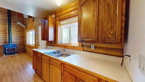 Kitchen featuring sink, rustic walls, a wood stove, and light wood-type flooring