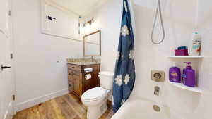 Full bathroom featuring tile walls, toilet, hardwood / wood-style flooring, vanity, and shower / tub combo with curtain